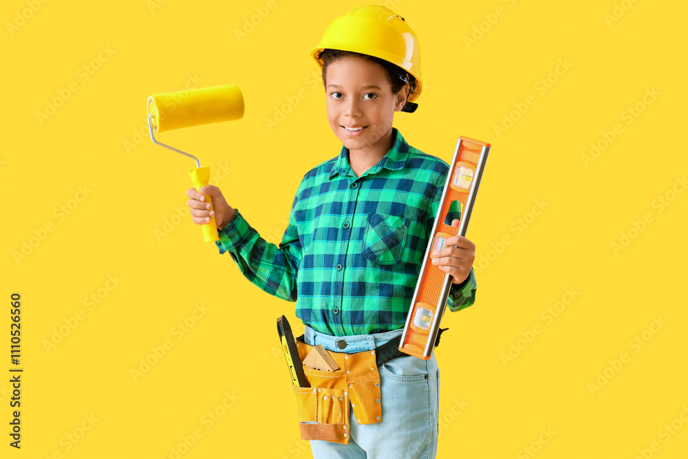 Cute little architect with paint roller and spirit level on yellow background Cute little architect with paint roller and spirit level on yellow background