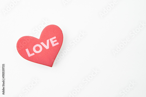 A red heart-shaped object with the word LOVE written on it placed on a white background
