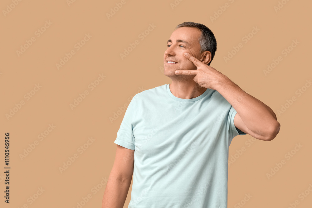Happy mature man doing face building exercise on beige background Happy mature man doing face building exercise on beige background