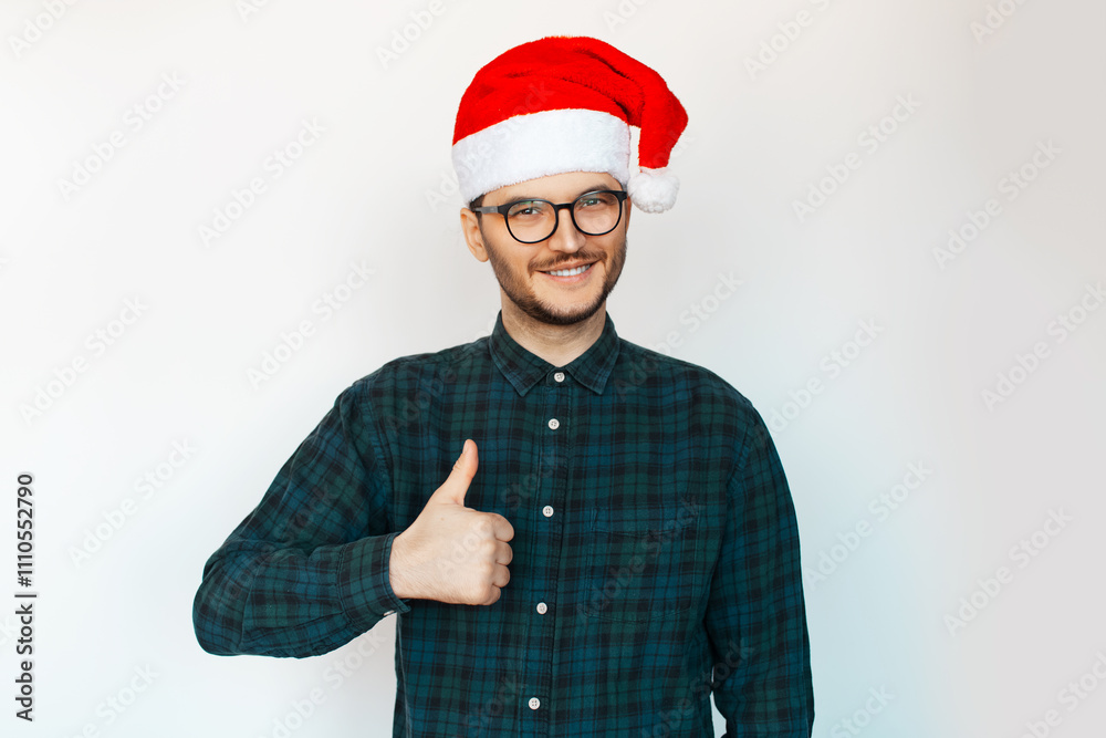 Portrait of young smiling man in Santa hat showing thumbs up on white background. Portrait of young smiling man in Santa hat showing thumbs up on white background.