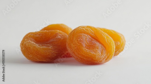 Three dried apricots are positioned neatly on a smooth surface, creating a clear background that is ideal for adding text or design elements related to snacks or health photo