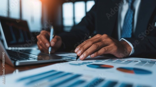 Business Analyst Reviewing Financial Charts and Graphs. Close-up of a business professional analyzing financial data with charts and graphs on a desk.