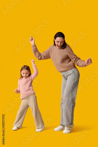 Mother and her daughter dancing on yellow background