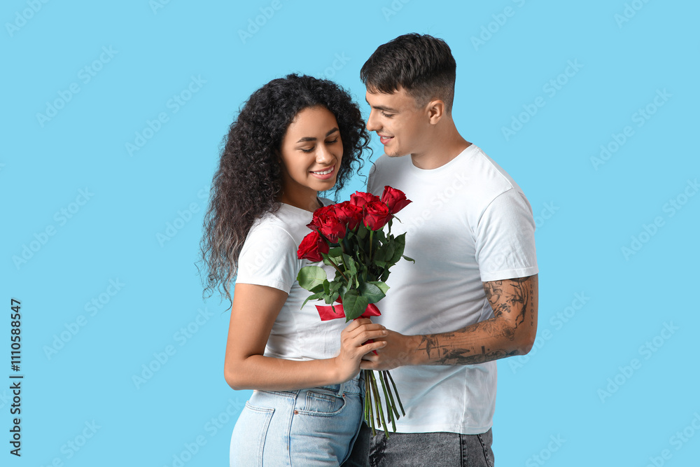 Loving young couple with bouquet of roses hugging on blue background. Valentine's Day celebration Loving young couple with bouquet of roses hugging on blue background. Valentine's Day celebration