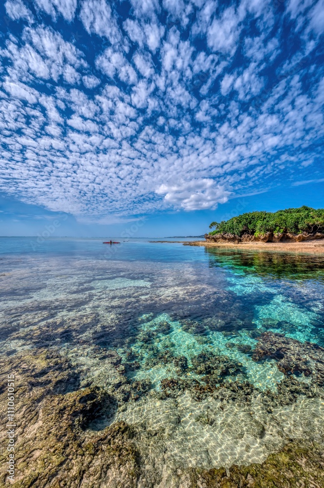 Fototapeta premium Crystal clear waters of Bise Beach, Motobu District, Okinawa main island. White sand beach with coral outcrops and small islands offshore.