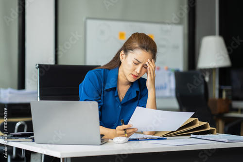 Serious businesswoman concentrating on his paper work at the table at office.