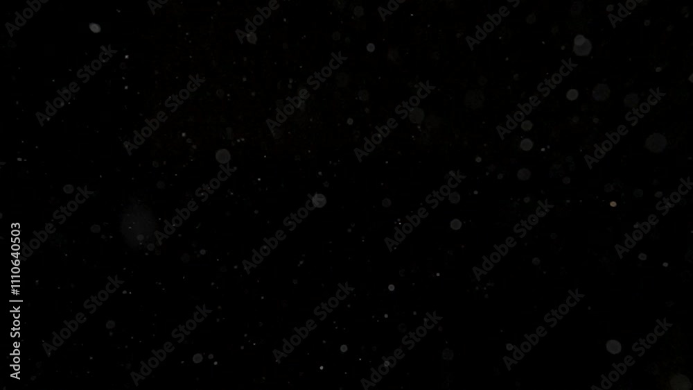 Many dust particles floating in light on empty black background with spotlight from above, close up view. Many dust particles floating in light on empty black background with spotlight from above, close up view.