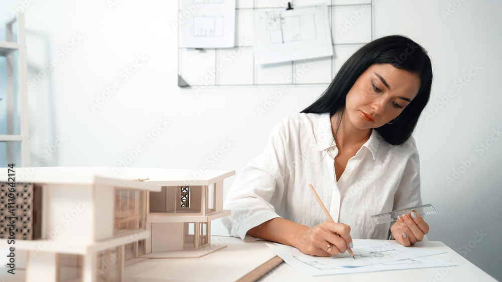 Closeup image of young architect engineer writing house structure in blueprint with document and architectural model placed on table at office. Creative design and architect concept. Immaculate. Closeup image of young architect engineer writing house structure in blueprint with document and architectural model placed on table at office. Creative design and architect concept. Immaculate.