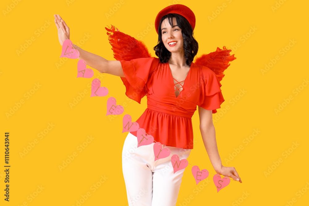 Beautiful young happy woman dressed as cupid with heart-shaped garland on yellow background. Valentine's Day celebration Beautiful young happy woman dressed as cupid with heart-shaped garland on yellow background. Valentine's Day celebration