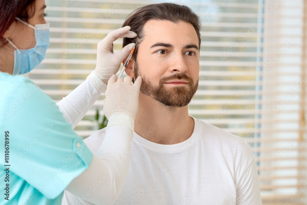 Obraz premium Handsome man receiving injection for hair growth in clinic