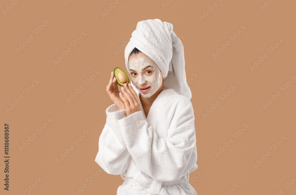 Beautiful young woman with applied facial mask and avocado after shower on brown background Beautiful young woman with applied facial mask and avocado after shower on brown background