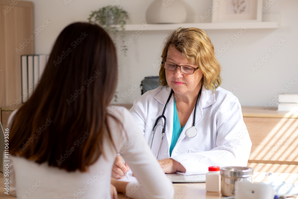 Senior woman doctor consults with young patient in modern medical office, doctor explaining and diagnosis with patient about health and treatment while writing on notes, medical and insurance. Senior woman doctor consults with young patient in modern medical office, doctor explaining and diagnosis with patient about health and treatment while writing on notes, medical and insurance.