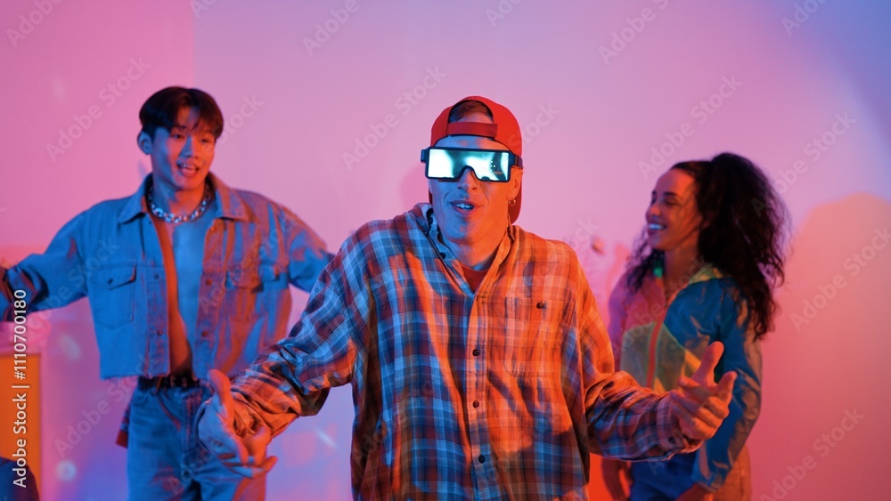 Diverse happy people moving to lively music with neon light at studio. Attractive hipster dancing while asian man show energetic movement while multicultural team cheering and supporting. Regalement. Diverse happy people moving to lively music with neon light at studio. Attractive hipster dancing while asian man show energetic movement while multicultural team cheering and supporting. Regalement.