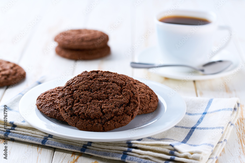 American chocolate cookies and coffee on a light kitchen table, selective focus. American chocolate cookies and coffee on a light kitchen table, selective focus.