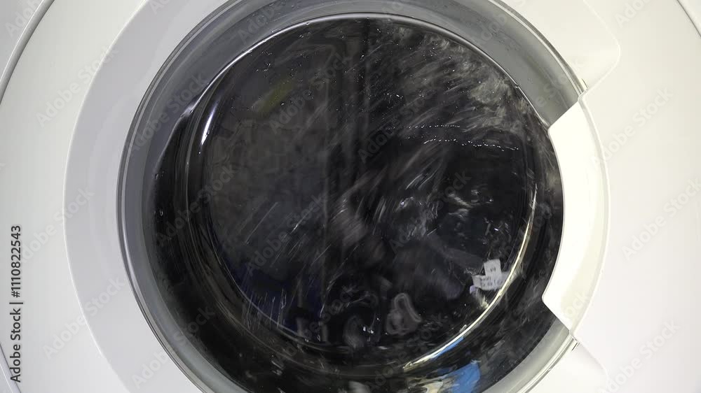 Close-up shot of a washing machine in motion, showcasing spinning laundry through the transparent door, capturing the dynamic energy of modern home appliances. Close-up shot of a washing machine in motion, showcasing spinning laundry through the transparent door, capturing the dynamic energy of modern home appliances.