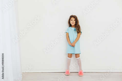 Little Curly Girl in Blue Dress on White Background
