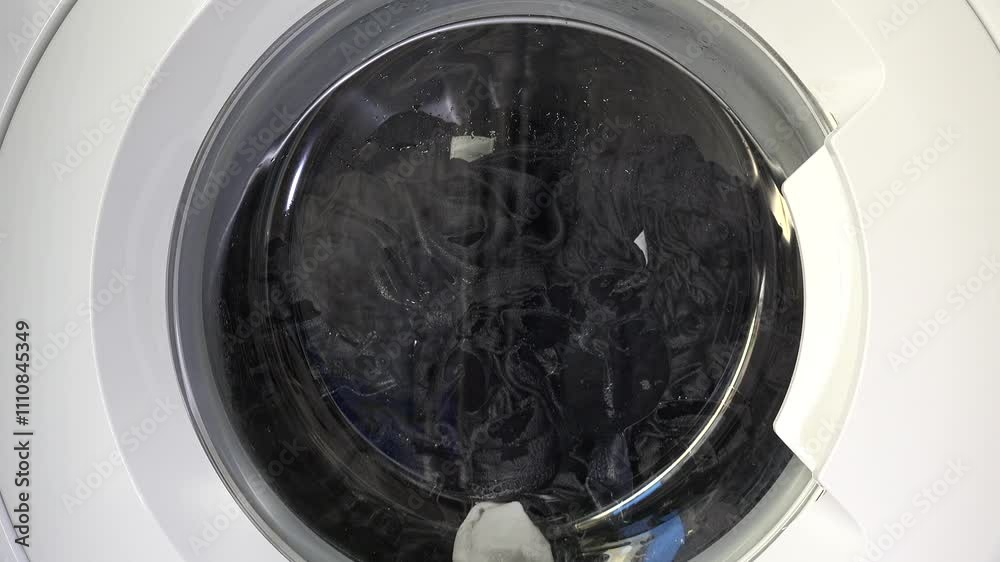 Close-up shot of a washing machine in motion, showcasing spinning laundry through the transparent door, capturing the dynamic energy of modern home appliances. Close-up shot of a washing machine in motion, showcasing spinning laundry through the transparent door, capturing the dynamic energy of modern home appliances.