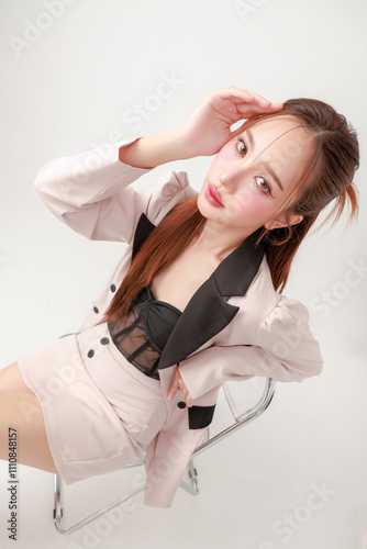 A fashionable woman in a stylish blazer poses elegantly with a modern chair.