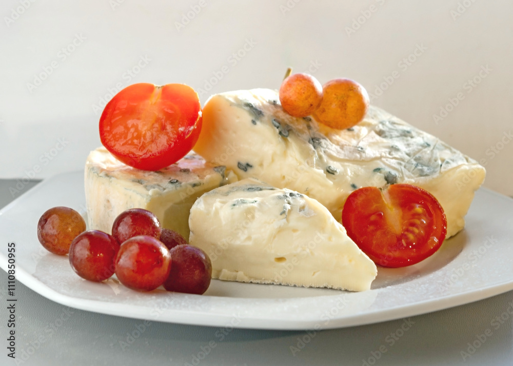 Blue Mold Cheese on White Plate with Tomatoes, Basil, and Grapes in Natural Light Blue Mold Cheese on White Plate with Tomatoes, Basil, and Grapes in Natural Light
