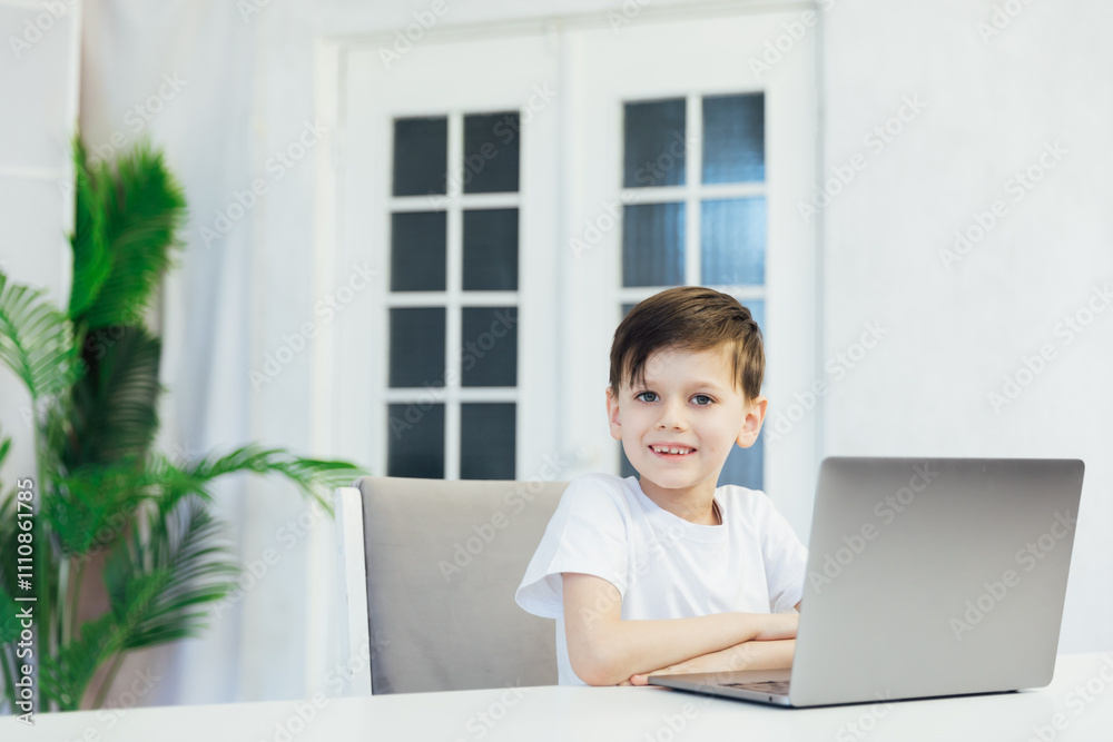 Little boy learning to play on laptop online at table Little boy learning to play on laptop online at table