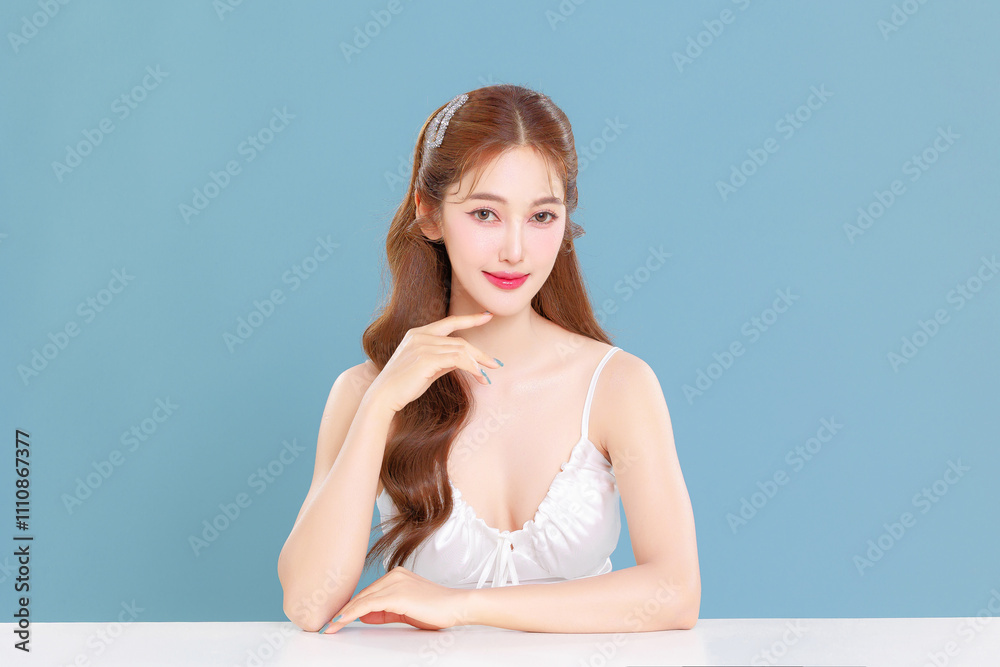 Pretty Asian beauty woman curly long hair with Korean makeup glowing face and healthy facial skin portrait smile on isolated blue background. Pretty Asian beauty woman curly long hair with Korean makeup glowing face and healthy facial skin portrait smile on isolated blue background.