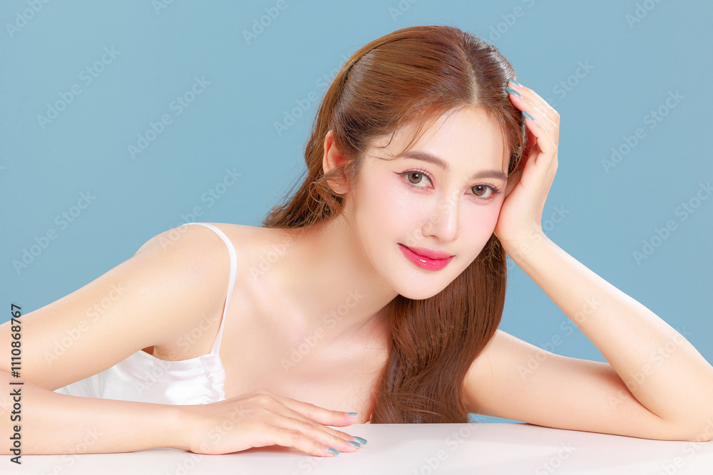 Pretty Asian beauty woman curly long hair with Korean makeup glowing face and healthy facial skin portrait smile on isolated blue background. Pretty Asian beauty woman curly long hair with Korean makeup glowing face and healthy facial skin portrait smile on isolated blue background.
