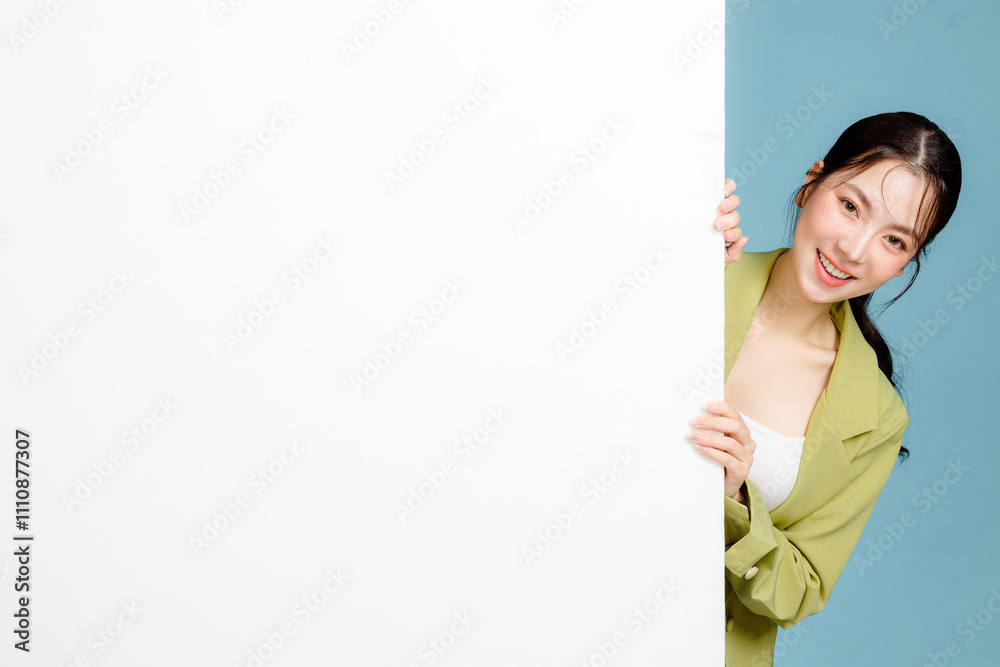 Young happy smiling successful employee business woman 20s in casual green jacket peeking out blank whiteboard isolated on pastel blue background. Female entrepreneurs, office worker concept. Young happy smiling successful employee business woman 20s in casual green jacket peeking out blank whiteboard isolated on pastel blue background. Female entrepreneurs, office worker concept.
