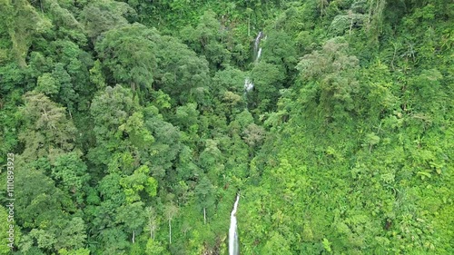 Aerial shot of Curug Cijalu ,beautiful hidden waterfall in green forest. Tropical mountain jungle waterfall in the tropical forest. Nature background photo