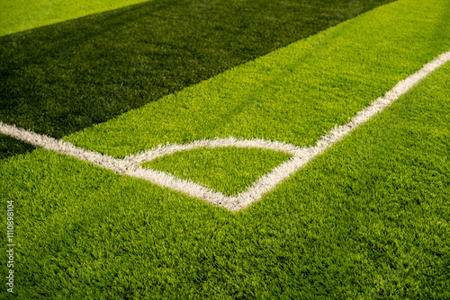 Close-up view of a mini soccer field corner with crisp white boundary lines and vibrant green grass, showcasing the well-maintained surface glowing under sunlight photo