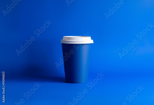 Blue disposable coffee cup against a monochromatic blue background, blank mockup