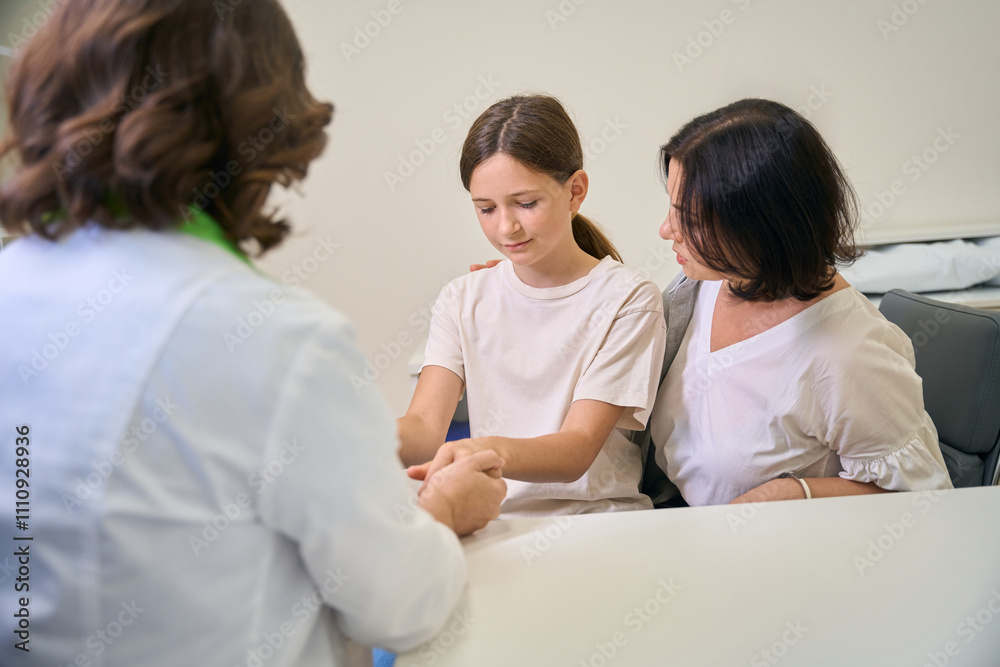 Pediatrician woman calms a teenage girl at a clinic appointment Pediatrician woman calms a teenage girl at a clinic appointment