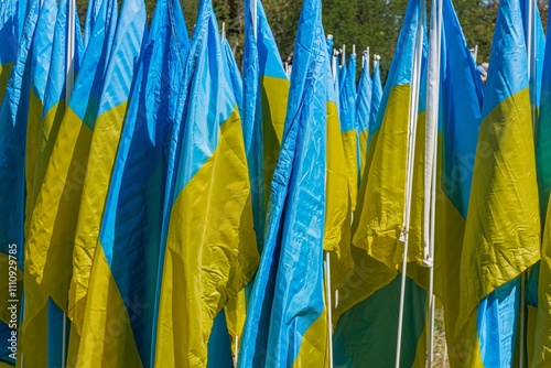 Collection of blue and yellow flags arranged in rows, moving due to wind No text visible background is neutral Realistic image taken during daylight Focus on colorful banners photo