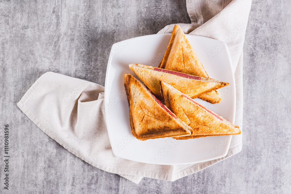 Close up of grilled triangle sandwiches with cheese and sausage on a plate on a table top view