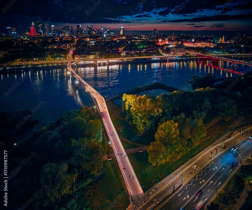 Beautiful panoramic aerial drone night sunset view to the new pedestrian and bicycle bridge connecting the banks of the Vistula, Warsaw, Poland.