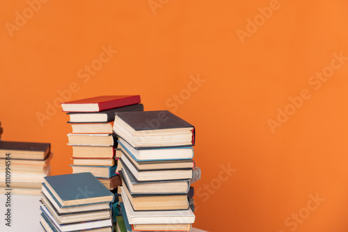 Stacks of books for reading and education in college library on orange background