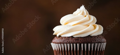 Moist chocolate cupcake topped with creamy vanilla frosting against a dark background