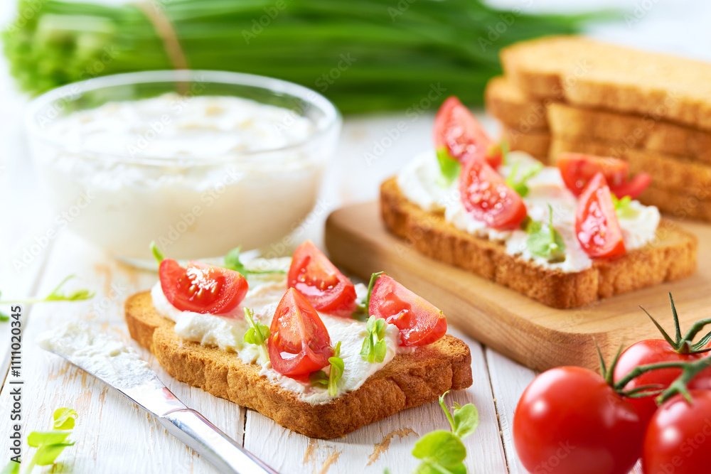 toasted bread with cream cheese, cherry tomatoes and green onion on a wooden table. toasted bread with cream cheese, cherry tomatoes and green onion on a wooden table.