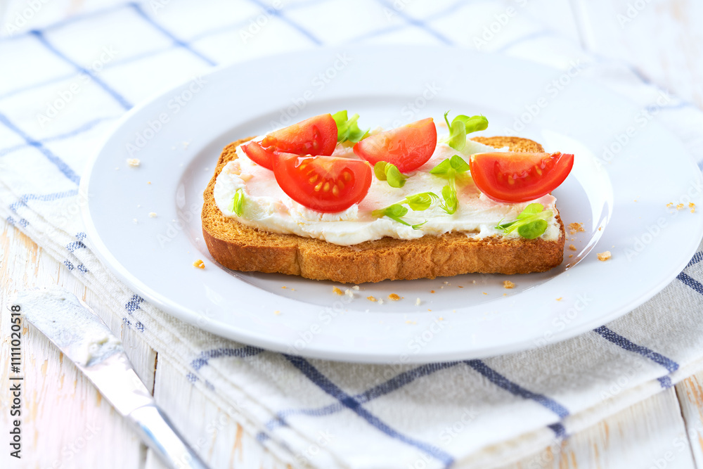Toasted bread with cream cheese and cherry tomatoes on the dinner table. A light appetizer for a party or picnic. Toasted bread with cream cheese and cherry tomatoes on the dinner table. A light appetizer for a party or picnic.