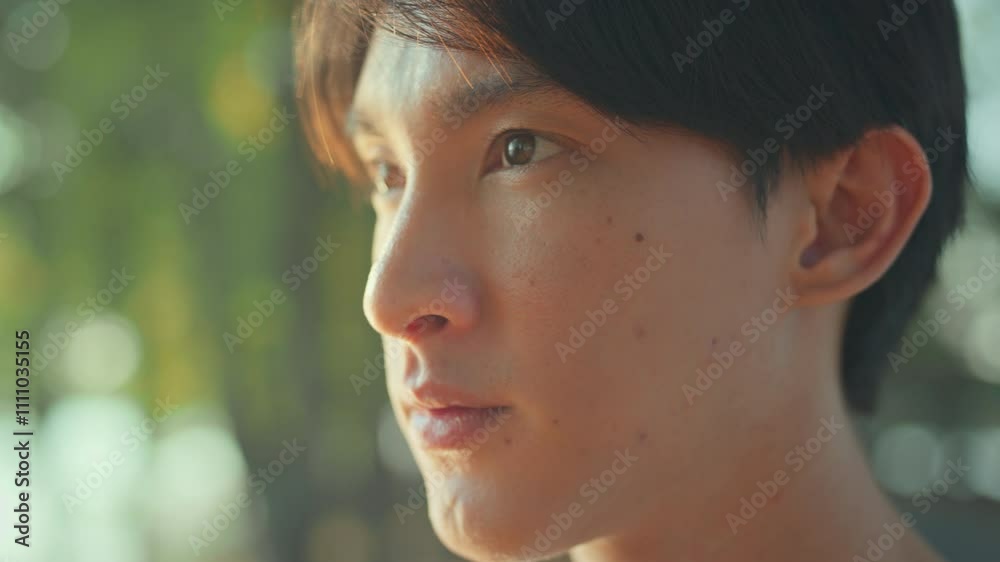Closeup of face asian male opening eyes looking straight while thinking of goal for exercise before running in public park