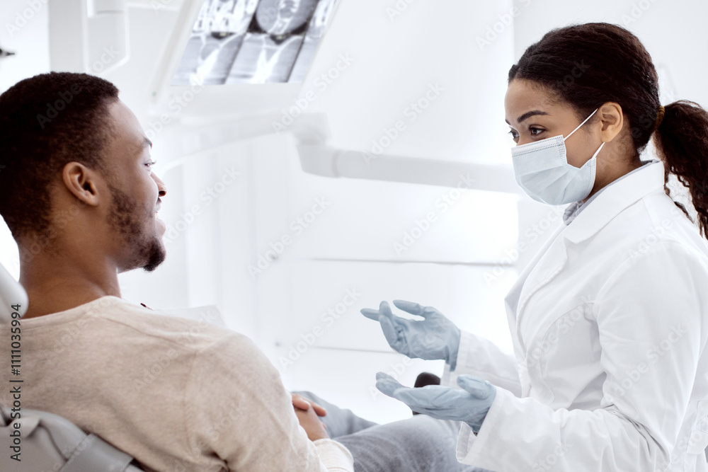 African American Stomatologist Woman Discussing Treatment Process With Male Patient During Check Up In Dental Clinic, Professional Teeth Doctor Lady Consulting Young Black Man, Closeup Shot African American Stomatologist Woman Discussing Treatment Process With Male Patient During Check Up In Dental Clinic, Professional Teeth Doctor Lady Consulting Young Black Man, Closeup Shot