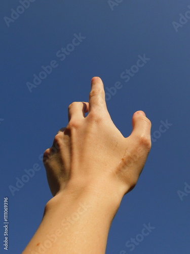 Hand pointing to the blue sky, first person perspective. 
