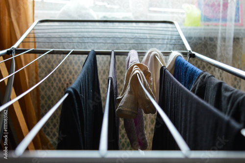 Slika na platnu a drying rack with various garments and textiles hanging to dry household laundr