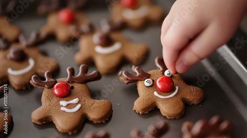 Cooking Christmas gingerbread. Child's hand decorating red nosed reindeer cookies with chocolate buttons and melted chocolate. Festive homemade decorated sweets photo