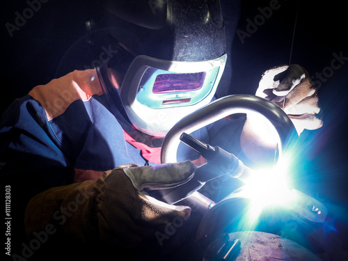 Skilled Industrial Welder Performing High-Precision TIG Welding in a Low-Light Environment