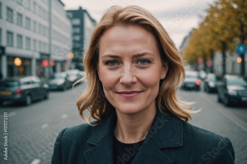 Close portrait of a smiling 40s Icelander businesswoman looking at the camera, Icelander big city outdoors blurred background