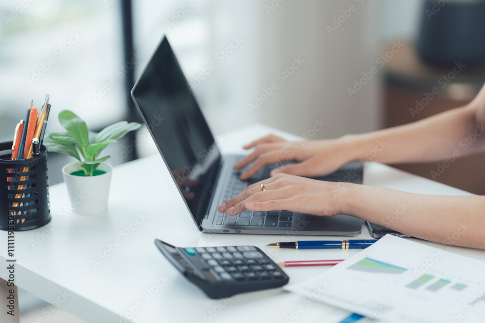 Focused on Finance: Close-up of hands typing on laptop, calculator and financial documents nearby, conveying productivity and efficiency in a modern workspace. Focused on Finance: Close-up of hands typing on laptop, calculator and financial documents nearby, conveying productivity and efficiency in a modern workspace.