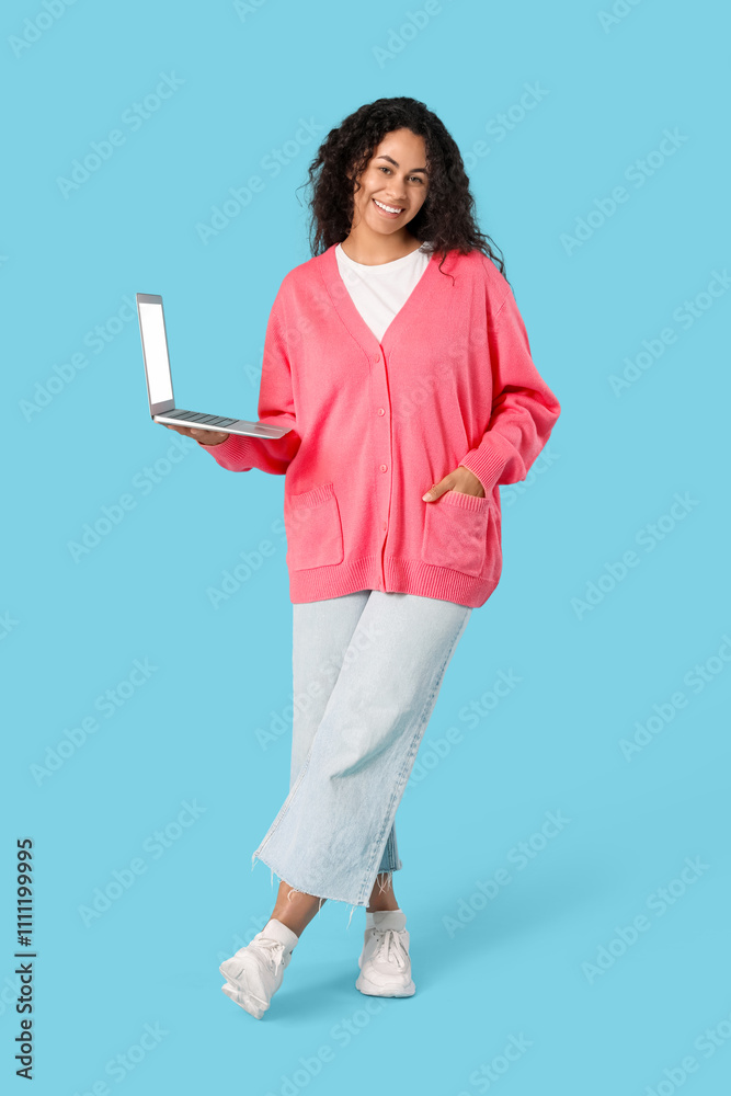 Young African-American QA engineer with laptop on blue background Young African-American QA engineer with laptop on blue background
