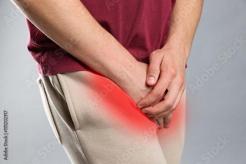 STD (sexually transmitted diseases). Man holding hands near his groin on grey background, closeup