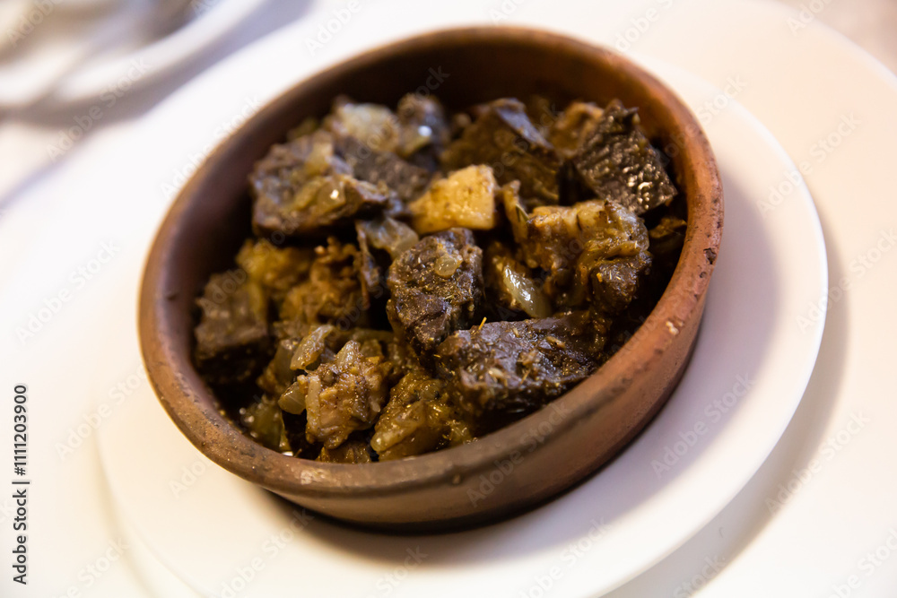 Traditional georgian dish with fried liver and vegetables in a brown ceramic bowl Traditional georgian dish with fried liver and vegetables in a brown ceramic bowl