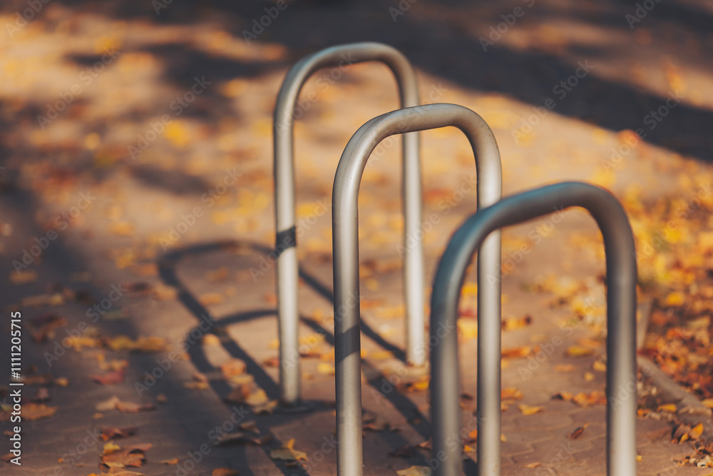 Bicycle parking to prevent theft. Bike locked up against metal pole in park. Closeup of steel bicycle rack on weathered wooden walkway with many small orange leaves. Bicycle parking to prevent theft. Bike locked up against metal pole in park. Closeup of steel bicycle rack on weathered wooden walkway with many small orange leaves.